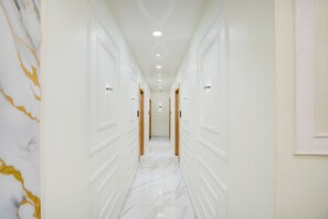 Un corridoio con pareti bianche, pavimento in marmo e porte su entrambi i lati.