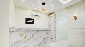 A reception area with a marble counter, a sign indicating a towerhouse, and a modern light fixture. - Townhouse Oak Prayagraj Allahabad (Prayagraj)