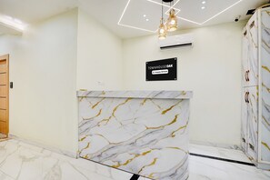 A reception desk with a marble design, a sign reading 'TOWNHOUSE OAK,' and an air conditioning unit on the wall. - Townhouse Oak Prayagraj Allahabad (Prayagraj)