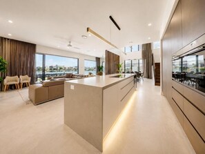 Cozinha moderna com ilha central, área de jantar com cadeiras e vista para a cidade.