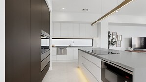 Eine moderne Küche mit Einbauofen, Spüle und Fernseher.