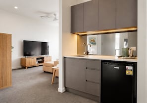 Uma cozinha moderna com máquina de lavar louça embutida, televisão de tela plana e sala de jantar com sofá.