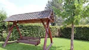 Un'altalena in legno con tetto in tegole in un giardino erboso.
