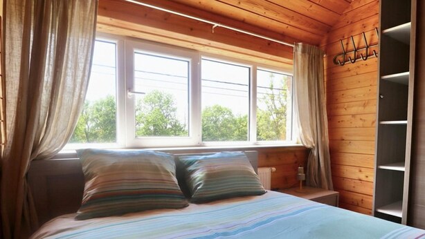 Una stanza con un letto, due finestre e un muro in legno.