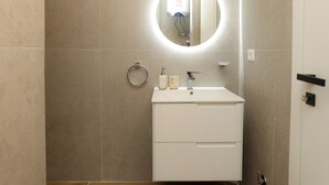 A bathroom with a white sink, a round mirror, a towel ring, and a toilet. - Majestic View Apartment Palm (Orikum)