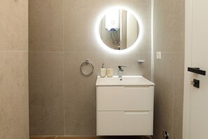 A bathroom with a white sink, a round mirror, a towel ring, and a toilet. - Majestic View Apartment Palm (Orikum)
