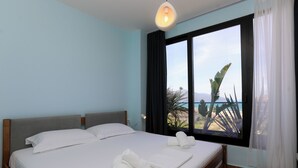 A hotel room with a bed, a window with curtains, and a view of the beach. - Majestic View Apartment Palm (Orikum)