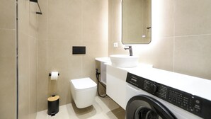 Un baño moderno con inodoro, lavabo, espejo y lavadora.
