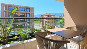 Un balcón con mesa y sillas, con vistas a una zona residencial con edificios modernos y un cielo despejado.