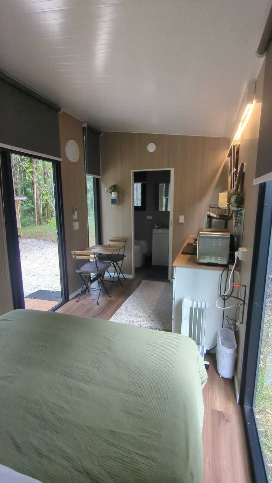 A modern room with a bed, a small kitchenette, a desk, and a view of the outdoors.