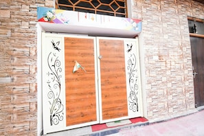 A double wooden door with decorative black patterns, set against a stone wall. - Townhouse Civil Lines Prayagraj (Prayagraj)