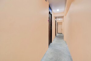 A corridor with beige walls and a concrete floor, leading to a door with a metal gate. - Townhouse Civil Lines Prayagraj (Prayagraj)
