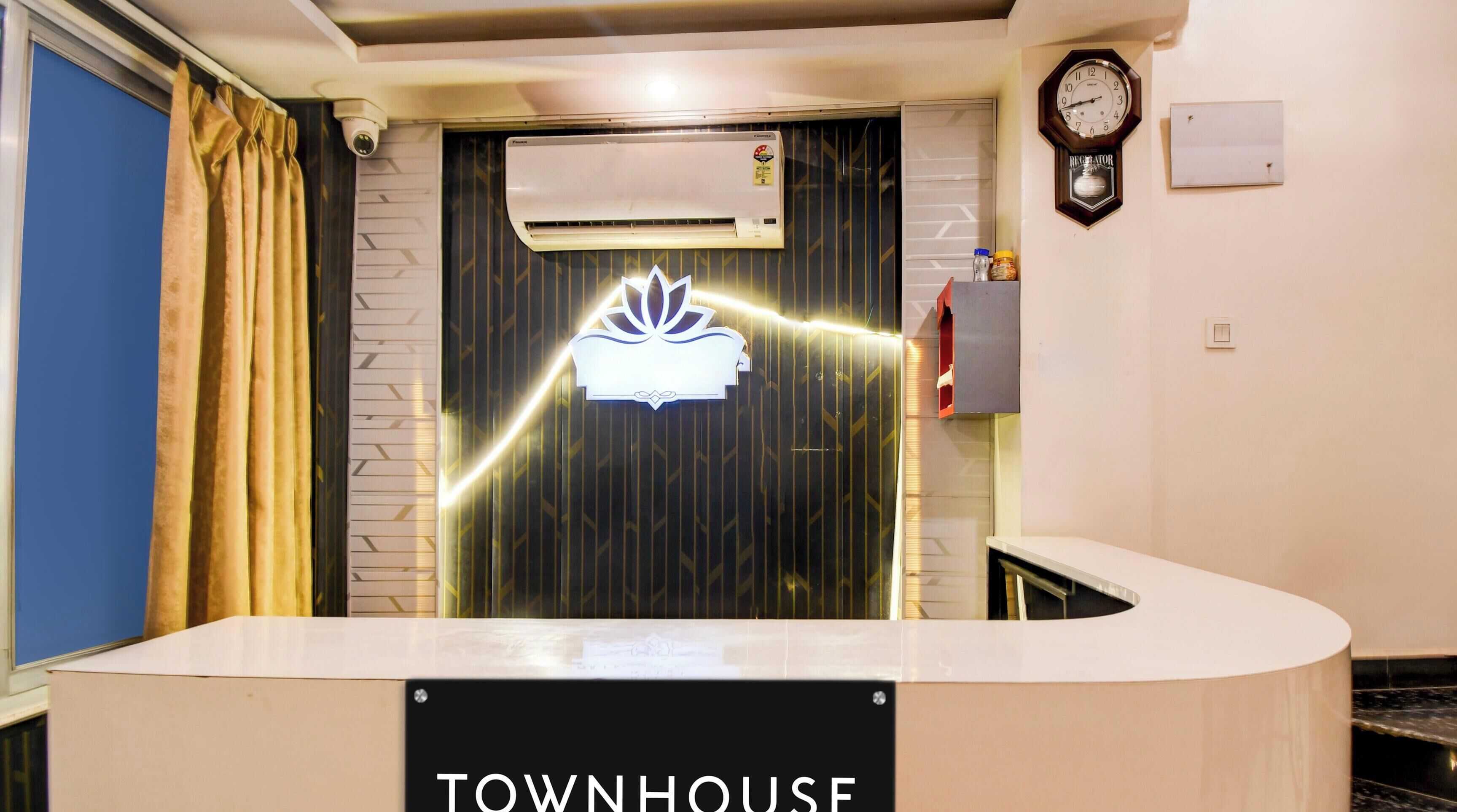 A reception desk with a sign reading 'TOWNHOUSE' and a clock on the wall.