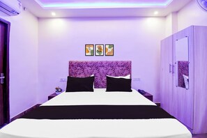 Un dormitorio con cama, cabecero, armario y cuadros en la pared.