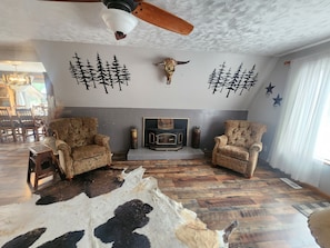 A cozy living room with two patterned armchairs, a fireplace, and decorative wall art.