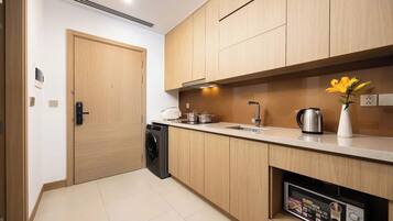 A modern kitchen with wooden cabinets, a built-in washing machine, a sink, and a microwave.