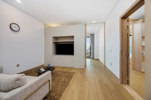 Una sala de estar moderna con un sofá, una mesa de centro, un televisor de pantalla plana y un reloj en la pared.