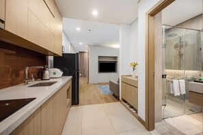 A modern kitchen with a built-in oven, a coffee maker, and a refrigerator. - Lancaster Apartment (Hanoi)