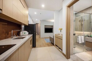 A modern kitchen with a built-in oven, a coffee maker, and a refrigerator. - Lancaster Apartment (Hanoi)
