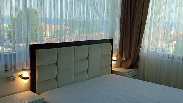 A hotel room with a bed, nightstands, and sheer curtains. - Empati Otel (Ayvalık)