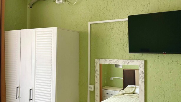 A room with a bed, a bedside table, a wardrobe, a mirror, and an air conditioning unit. - Empati Otel  (Ayvalık)