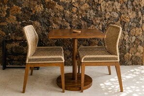 A round wooden table with two wicker chairs.