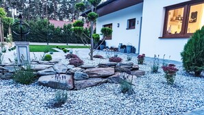 Ein modernes Haus mit Steingarten, gepflegtem Rasen und einem sichtbaren Küchenfenster.