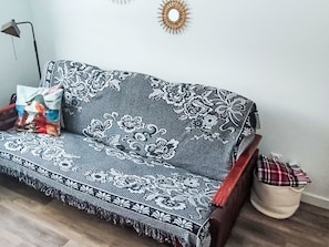 A sofa with a floral pattern, a lamp, and a decorative wall piece.