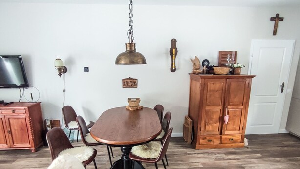 Ein Essbereich mit einem runden Tisch, Stühlen, einer Holzschrank und einem Fernseher an der Wand.