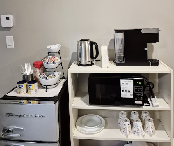 Una kitchenette equipada con refrigerador, microondas, tetera y cafetera.