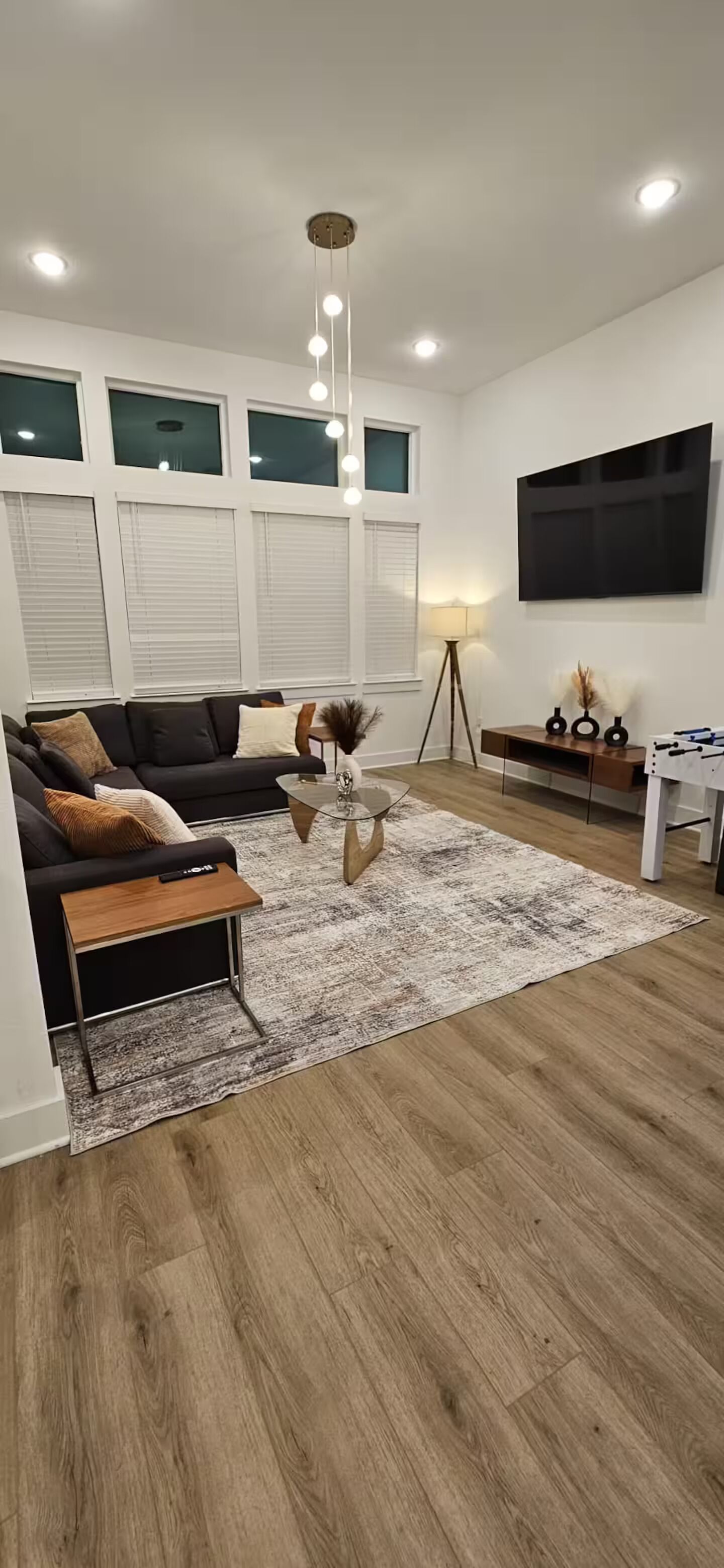 A modern living room with a sofa, coffee table, and a flat-screen TV mounted on the wall.