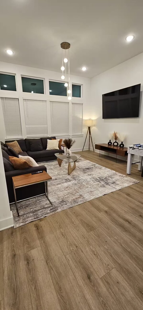 A modern living room with a sofa, coffee table, and a flat-screen TV mounted on the wall.