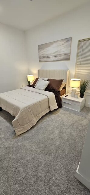 Une chambre à coucher avec un lit, des tables de chevet, une lampe, une plante et un tableau au mur.