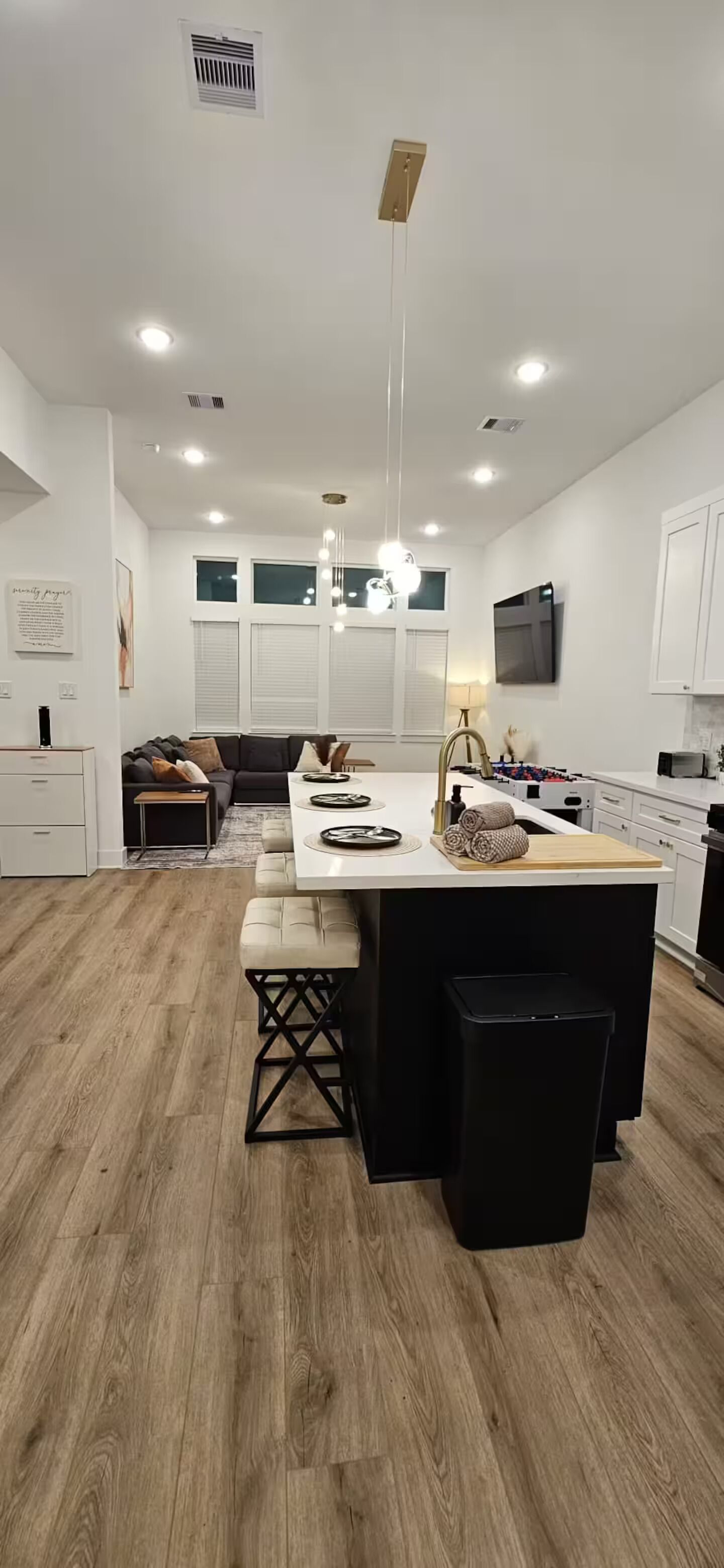 A modern kitchen with a central island, bar stools, and a dining table.