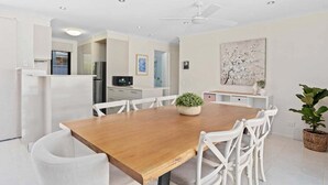 A modern kitchen with white cabinetry, a wooden dining table, and white chairs. - Relax at Riviera - Villa in Miami (Gold Coast)