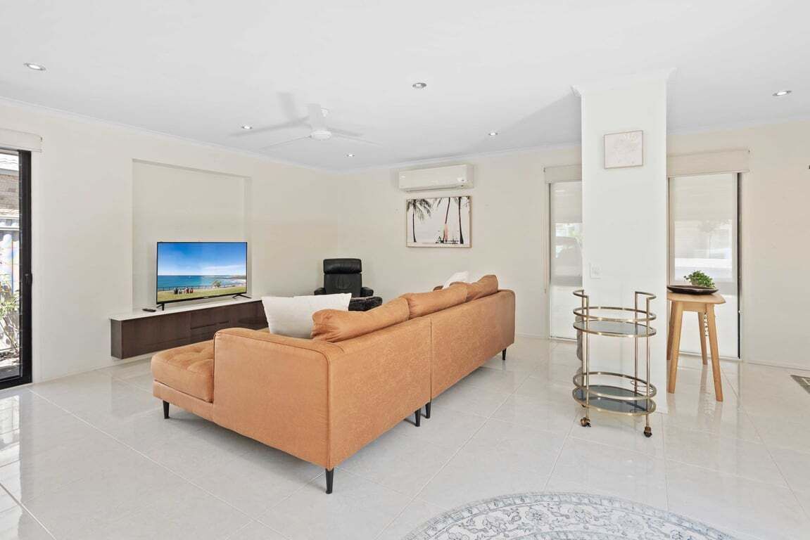 A modern living room with a sofa, TV, and a ceiling fan.