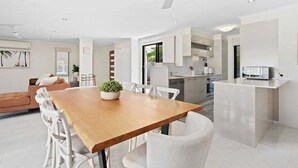 A modern kitchen with white cabinets, a wooden dining table, and a ceiling fan. - Relax at Riviera - Villa in Miami (Gold Coast)