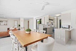 Eine moderne Küche mit weißen Schränken, einem Holztisch und einem Deckenventilator.