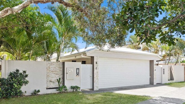 A residential property with a garage, a stone wall, and a well-maintained lawn. - Relax at Riviera - Villa in Miami (Gold Coast)