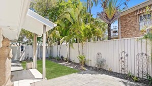 A backyard with a patio, a white fence, and various plants. - Relax at Riviera - Villa in Miami (Gold Coast)
