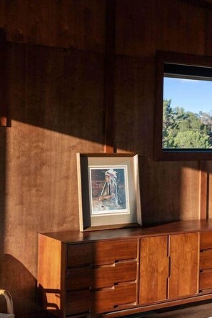 A wooden cabinet with drawers, a framed picture, and a television on a wall. - The Moki House (with hot tub) (Wayne County)