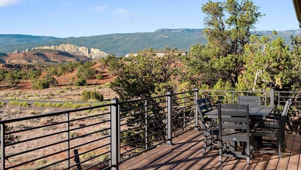 A deck with a table and chairs overlooking a mountainous landscape. - The Moki House (with hot tub) (Wayne County)
