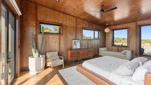 A bedroom with a large bed, a wooden ceiling, a ceiling fan, and a window with a view of the outdoors. - The Moki House (with hot tub) (Wayne County)