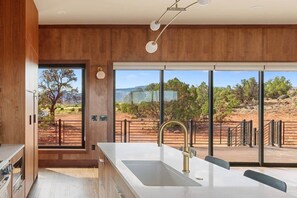 A modern kitchen with a large window, a sink, and a view of a desert landscape. - The Moki House (with hot tub) (Wayne County)