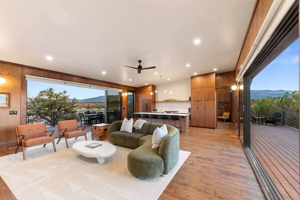 A modern interior with a sofa, chairs, a dining area, and a kitchen. - The Moki House (with hot tub) (Wayne County)