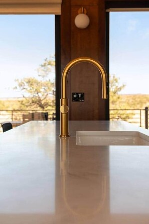 A kitchen with a gold faucet, a marble countertop, and a view of the outdoors. - The Moki House (with hot tub) (Wayne County)