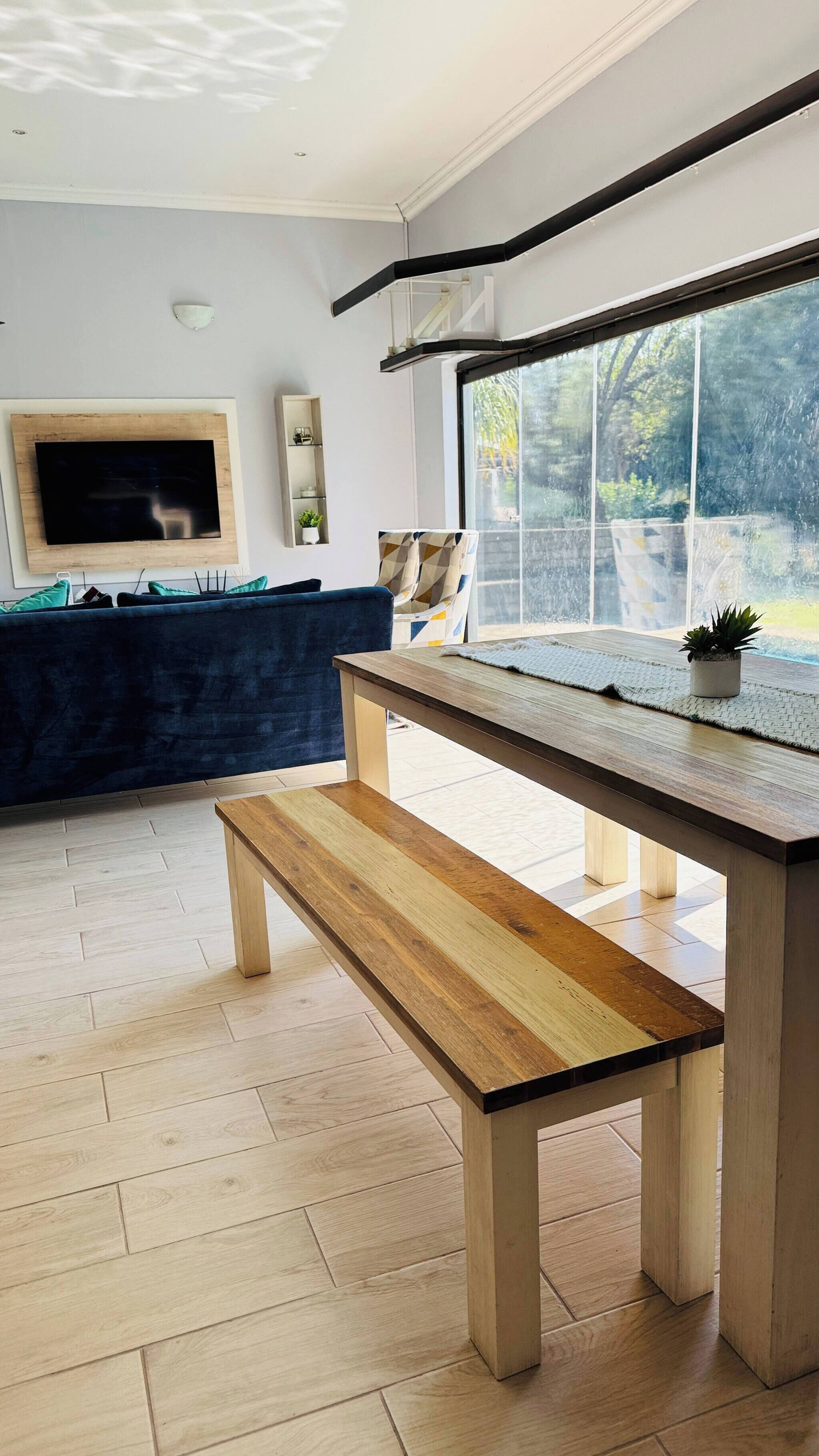 Un salón moderno con un banco de madera, un televisor en la pared y un ventanal con vistas al exterior.