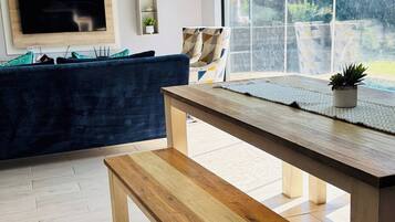 Un salón moderno con un banco de madera, un televisor en la pared y un ventanal con vistas al exterior.