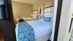 A hotel room with a bed, a bedside table, a lamp, and a painting on the wall. - Beautiful 4-br House on 51 Pecanwood (Hartbeespoort)