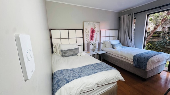 Habitación de hotel con dos camas, un ventanal grande y vista a zonas verdes.